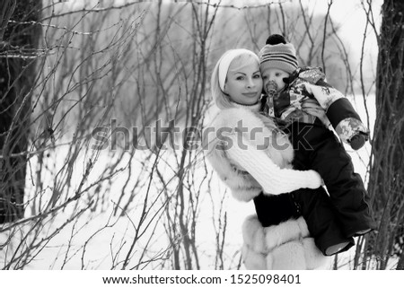 A young mother walks on a winter day with a baby in her arms in the park
