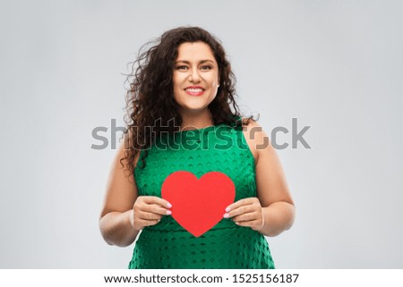 valentine's day, people and love concept - happy woman in green dress holding red heart over grey background
