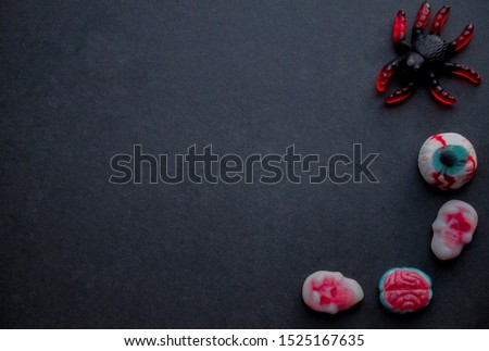 Jelly candies in the form of eyes, brains, skulls and spider  in the lower right corner on a black background. Copy space