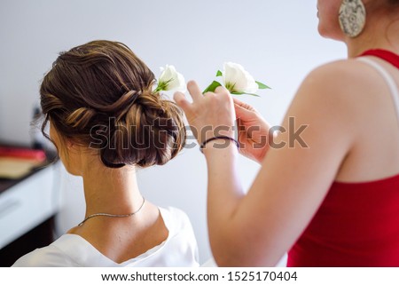 Bride getting her hair done by a hair stylist. Fresh rose flowers decoration