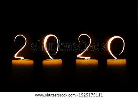 2020 written with candle flames on black background, greeting card
