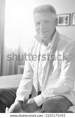 Black and white photo of senior man sitting on bed
