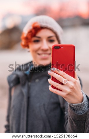 Woman making photo of beautiful sea landscape on mobile phone. Happy smiling woman walking outdoors, using smartphone, taking selfie, picture of sunset nature.