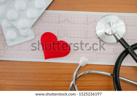red heart on a cardiogram, stethoscope and pills. Medical concept.