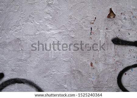 white painted weathered grunge wall with black graffiti tag spray paint scribble features