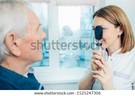 Doctor Optometrist examining old man's eyes with special eye equipment