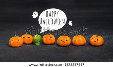Happy Halloween greeting card. orange decorative pumpkins, ghost and green frog toy on black background. halloween holiday concept