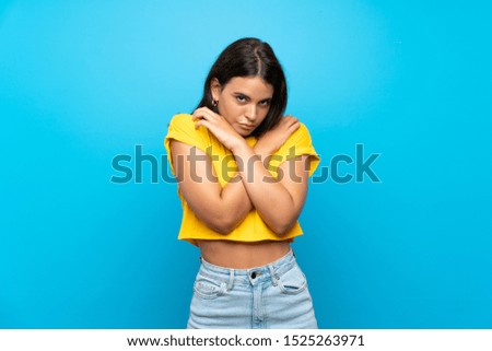 Young girl over isolated blue background freezing