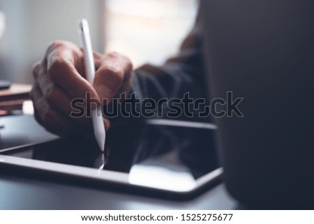 Business man hand using stylus pen signing electronic contract on digital tablet computer to make a deal. Web designer create his work on tablet pc and laptop computer, business and technology concept