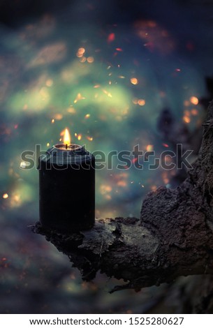 black burning candle in autumn mystery forest. esoteric witchcraft ritual. magic fall seasonal Background. samhain sabbat, Halloween holiday concept. template for design Royalty-Free Stock Photo #1525280627