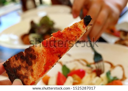 Slice of Marinara Pizza with other food in background 