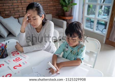 portrait of unhappy mother while teaching her daughter at home