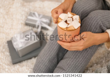Young woman with cocoa sitting on light blanket, closeup. Christmas holiday