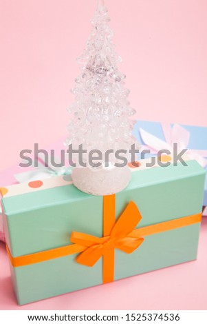 glass white Christmas tree with gifts with bows on a pink background
