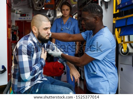 Emergency doctors providing medical care to injured man in ambulance car Royalty-Free Stock Photo #1525377014