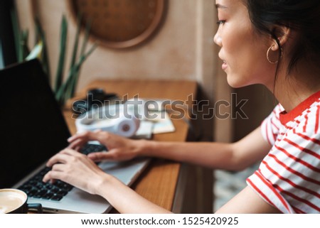 Cropped picture of a young beautiful asian woman sit in cafe using laptop computer.