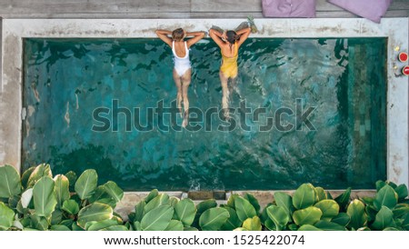Family mom and teen child relaxing at pool on Bali private villa, top view from above