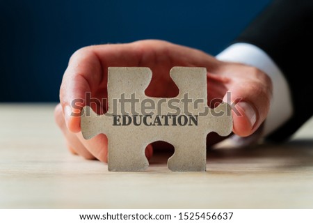 Male hand holding a puzzle piece with education sign on it.