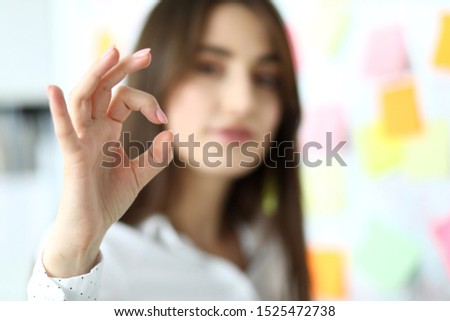 Female clerk showing all right symbol with her fingers at office workplace close-up