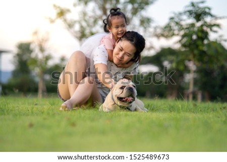 Beautiful happy family is having fun with french bulldog outdoors. 
