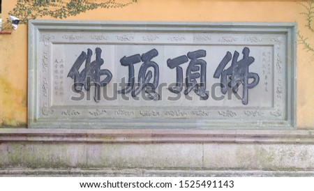 Four Chinese handwriting characters on yellow temple wall which means Buddha on top of foding mountain in Putuo island in Zhejiang, China.