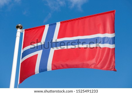 Flag of Norway waving in the wind in front of blue sky