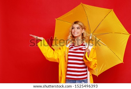 young happy emotional cheerful girl laughing and jumping with yellow umbrella   on colored red background
