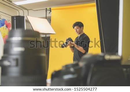 A young male photographer is checking the image on the camera and thinking. For working in studio concept.