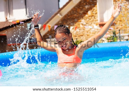 Happy black girl portrait splash in a swiming pool