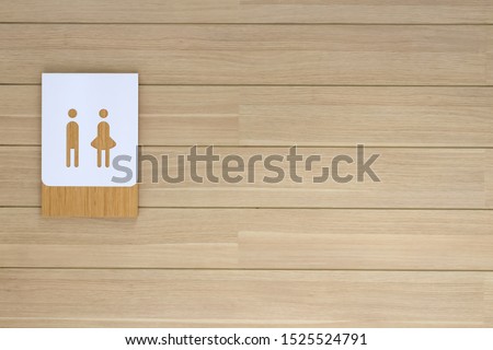 New white toilet sign on beige wooden plank wall on the way to restroom.