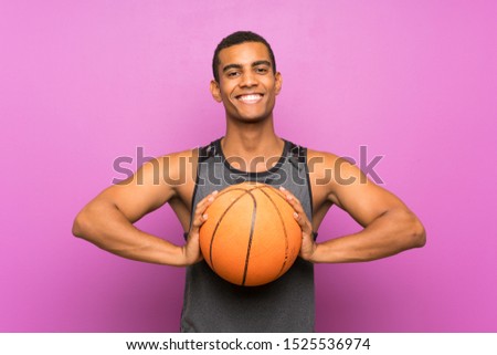 Young sport man with ball of basketball over isolated purple wall