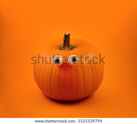 Halloween pumpkin with eyes stock images. Halloween pumpkin with eyes on a orange background. Cute halloween pumpkin with chocolate eyes. Single pumpkin isolated on orange background