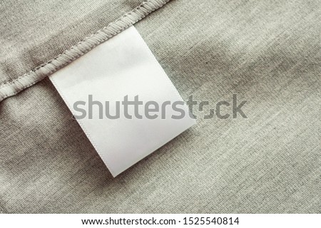 White blank laundry care clothing label on gray fabric texture background