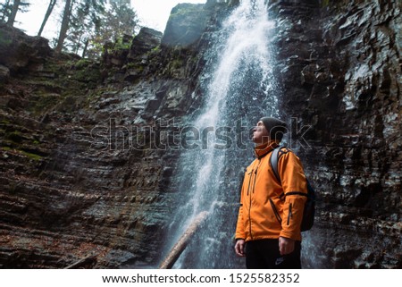 man hiking concept looking at waterfall in dip forest