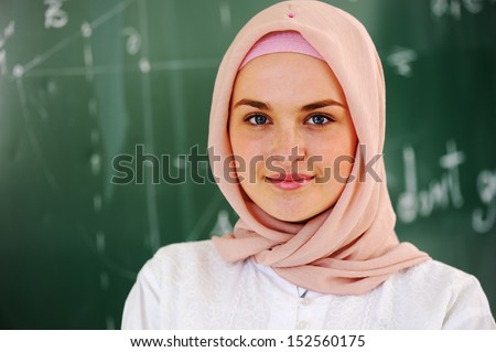 Arabic Muslim teenage student inside the high school classroom posing on board