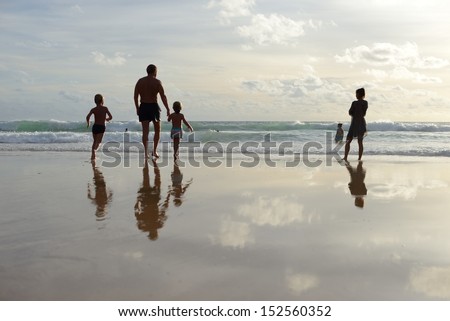 Family walking with reflection on the beach