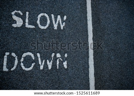 Top view of asphalt road with white text Slow Down and line.