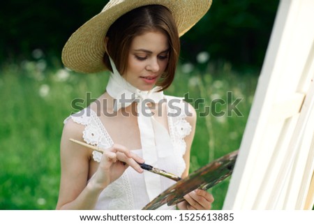 young beautiful woman in nature draws a picture