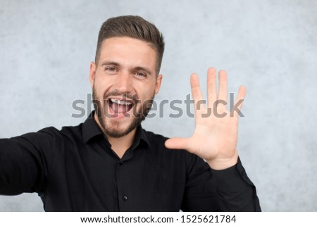 Portrait of smiling man with hand raised in greeting. High five concept