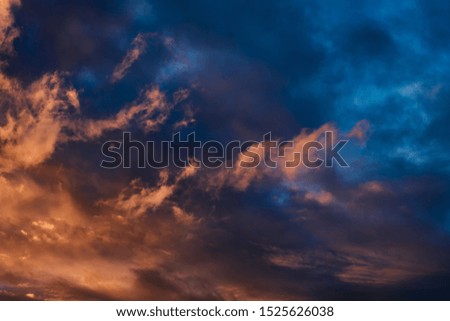 Dramatic sky at sunset or sunrise with red and orange clouds. Variegated colored clouds at the evening sunset of the summer sky.