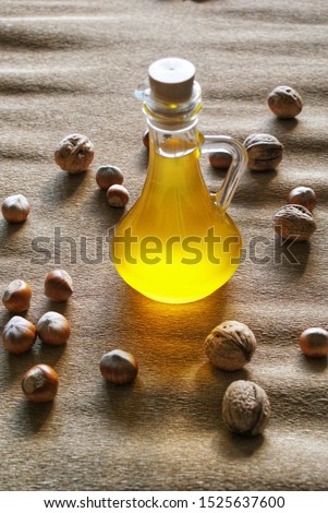 golden sunflower oil in a small bottle on a background of nuts. Eco farm, eco products, clean, friendly, eco food, vegan. Royalty-Free Stock Photo #1525637600
