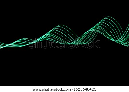 Long exposure photograph of neon green colour in an abstract swirl, parallel lines pattern against a black background. Light painting photography.