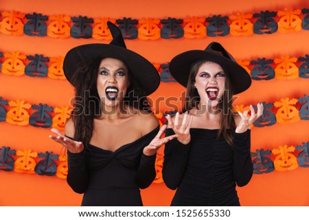 Image of furious witch women in black halloween costume and makeup screaming and looking upward isolated over orange pumpkin wall