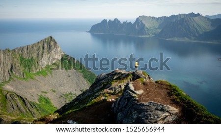 Adventurous man is standing on top of the mountain and enjoying the beautiful view during a vibrant sunset. Beautiful Nature Norway natural landscape aerial photography