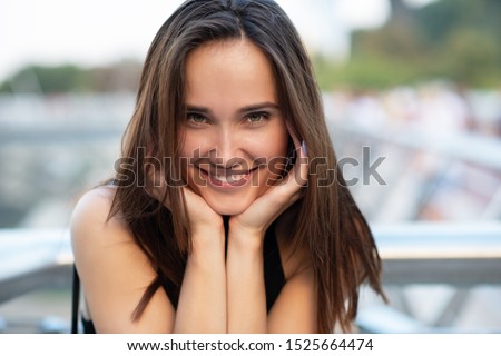 Young pretty likable cheerful woman posing summer city outdoor in Kyiv, Ukraine. Beautiful self-confident girl with long brown hair posing on Dnipro river bank enjoing her life, urban lifestyle Royalty-Free Stock Photo #1525664474