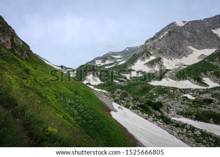 Amazingly beautiful landscape near Mount Oshten with green field and remaining snow, Adygea, Russia
