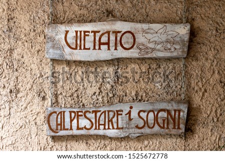 old wooden sign with the words "don't step on dreams" in italian language