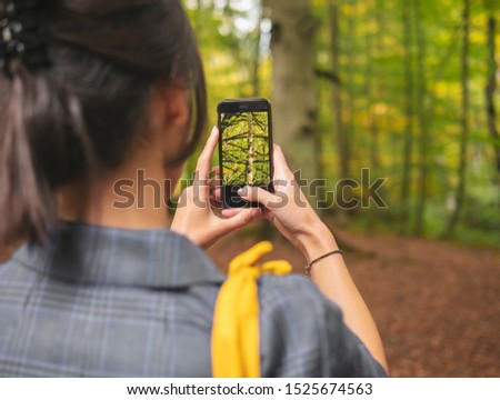 Girl taking photo of tree and nature using the phone