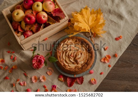 apple pie, charlotte on a linen gray tablecloth next to a box of apples Royalty-Free Stock Photo #1525682702