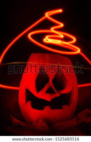 Halloween pumpkin on a background of burning coals. Ominous pumpkin with red luminous stripes. Vertical photograph. Orange-red jack head with a creepy smile. Halloween 2019